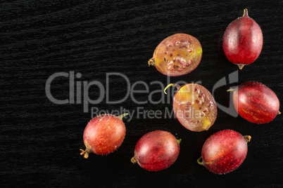 Fresh raw red gooseberry on black wood