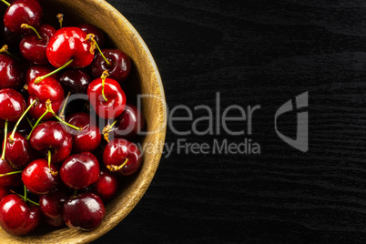 Fresh raw sweet red cherry on black wood