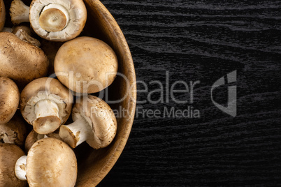 Fresh raw brown champignons on black wood