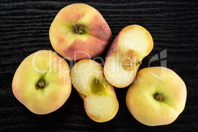 Fresh raw saturn peach on black wood