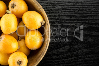 Fresh raw orange japanese loquat on black wood