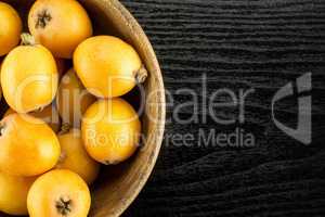 Fresh raw orange japanese loquat on black wood