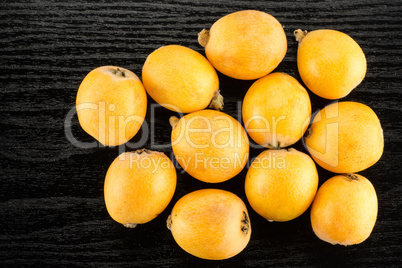 Fresh raw orange japanese loquat on black wood