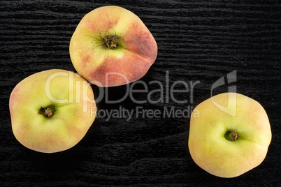 Fresh raw saturn peach on black wood