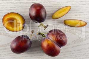 Fresh Raw vibrant plums on grey wood