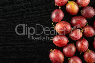 Fresh raw red gooseberry on black wood