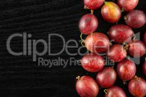 Fresh raw red gooseberry on black wood