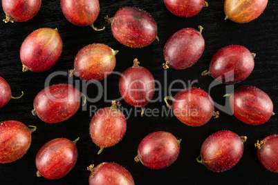 Fresh raw red gooseberry on black wood