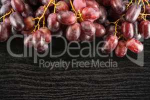 Raw fresh red globe grape on black wood