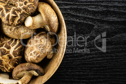 Fresh raw shitake mushroom on black wood