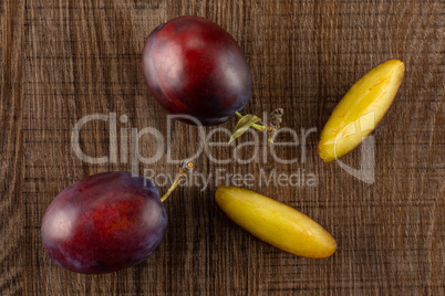 Fresh Raw vibrant plums on brown wood