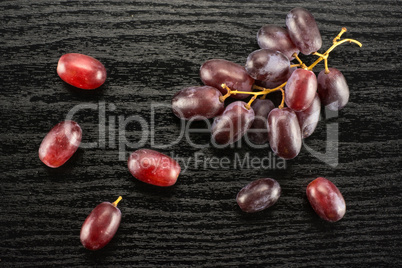 Raw fresh red globe grape on black wood