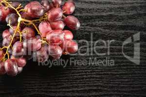 Raw fresh red globe grape on black wood