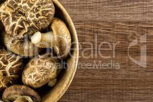 Fresh raw shitake mushroom on brown wood