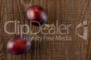 Fresh Raw vibrant plums on brown wood