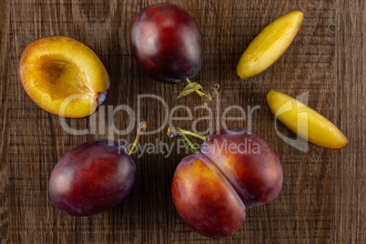 Fresh Raw vibrant plums on brown wood