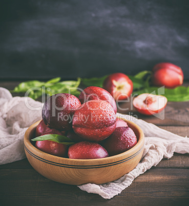 red ripe peaches nectarine in a brown wooden bowl
