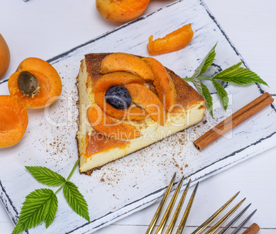 piece of cheesecake with apricots on a white wooden board