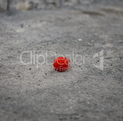 red woolen ball lies on the gray asphalt