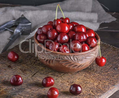 ripe fresh cherry in a brown ceramic bowl on a wooden board