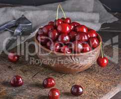 ripe fresh cherry in a brown ceramic bowl on a wooden board