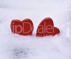 two red wooden hearts lie on white snow