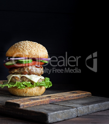 large burger with two fried cutlets, cheese and vegetables