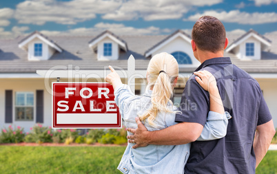 Young Adult Couple Facing and Pointing to Front of For Sale Real
