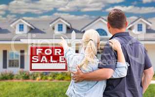 Young Adult Couple Facing and Pointing to Front of For Sale Real