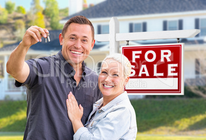 Young Adult Couple With House Keys In Front of Home and For Sale