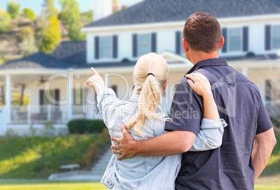 Young Adult Couple Facing and Pointing to Front of House