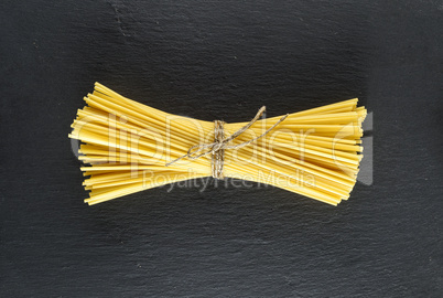 raw spaghetti tied with a rope on a black background