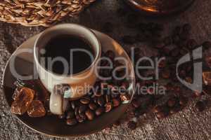 cup of coffee on textile with beans, dark candy sugar, pots, basket