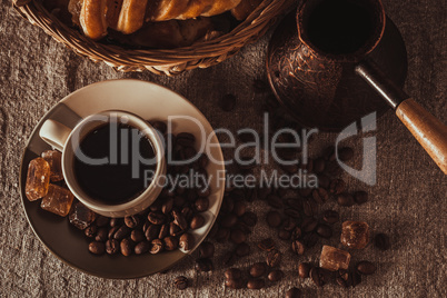 top view cup of coffee with beans, dark candy sugar, pot, basket and cake