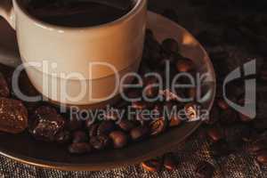 Cup on saucer with scattering of coffee beans and sugar