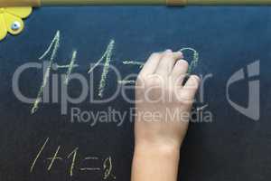 The girl writes in chalk on the blackboard.