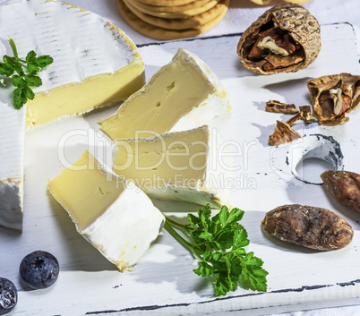 Camembert cheese sliced on a white wooden board
