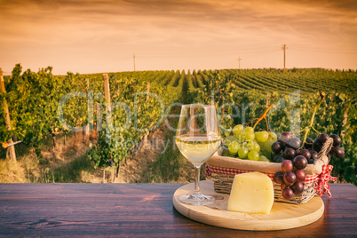 Glass of white wine in front of a vineyard at sunset