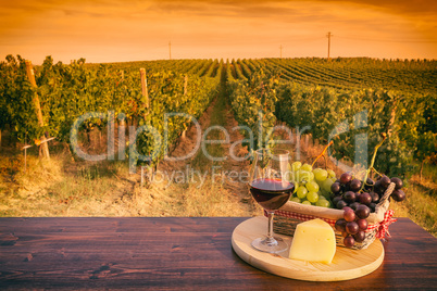 Glass of red wine in front of a vineyard at sunset