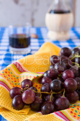Closeup of a bunch of red grapes and a glass of red wine with a