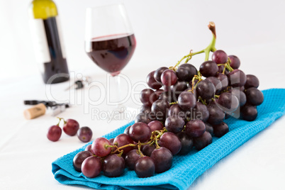 Closeup of a bunch of red grapes and a glass of red wine with a