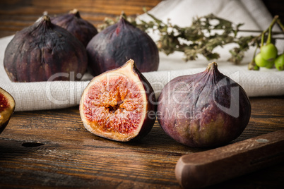 Ripe, purple figs on wooden table with sliced one