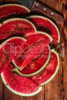 Watermelon slices with knife lying on wooden table