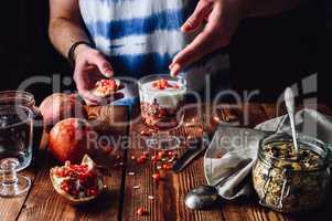 Man Decorates Dessert with Pomegranate Seeds.