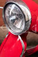 Red Vespa scooter front light.