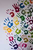 Colorful handprints on a white concrete wall.