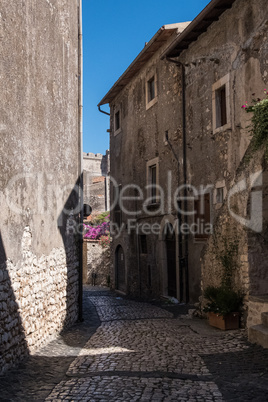 Medieval town alley with the wall of a castle in the background.