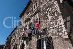 Red and green clothes hanged in front of an old stone medieval h