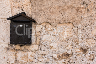 Metal mailbox with rough stone wall background.