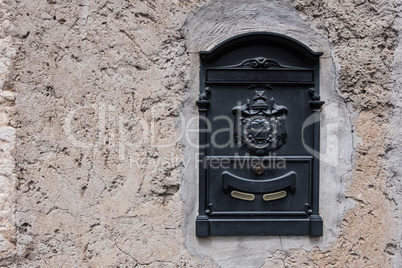 Metal mailbox with rough concrete wall background.